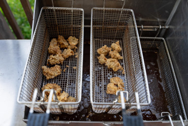 Freshly fried Louisiana oysters resting in two baskets above a fryer.