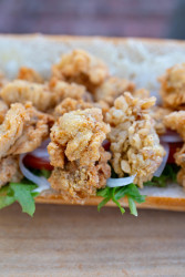 A close-up view of freshly fried Louisiana oysters in a fried oyster poboy.