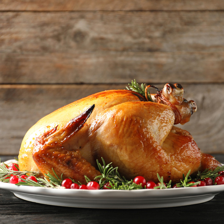 Cooked, golden turducken on a platter with greens and cranberries
