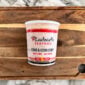 A plastic container of crab and corn soup, served like Rachael’s Crawfish Etouffee, on a wooden cutting board.