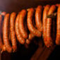 Poche’s Smoked Alligator and Pork sausage links hanging on a wooden rack.