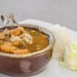 A bowl of Rachael’s Seafood Gumbo with a scoop of white rice and a side of potato salad.