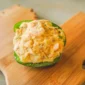 A Rachael’s stuffed bell pepper half filled with shrimp and grains on a wooden cutting board.