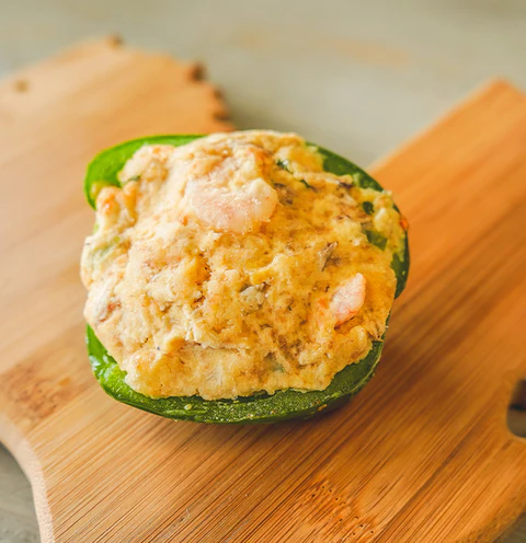 Rachael's Stuffed Bell Pepper (2) A Rachael’s stuffed bell pepper half filled with shrimp and grains on a wooden cutting board.