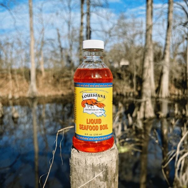 bayou 8 oz An 8oz bottle of LA Crawfish Co. Liquid Boil rests on a wooden post before a bayou.