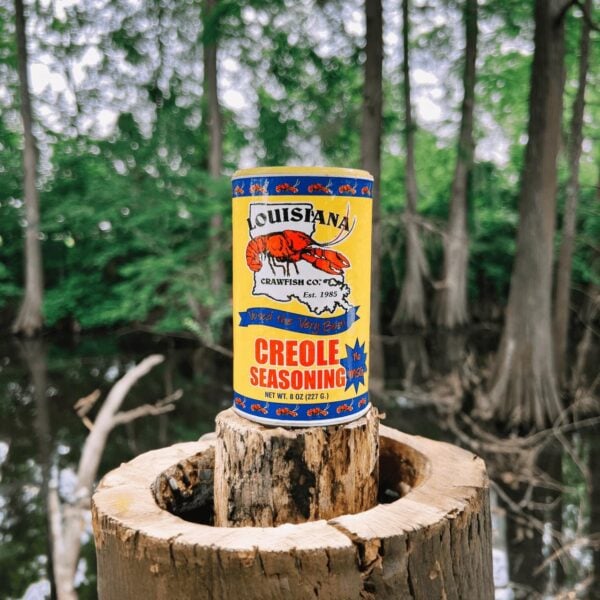 bayou creole no msg A yellow canister of LA Crawfish Co. Creole Seasoning stands on a tree stump before a bayou.