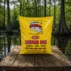 A 4 lb bag of LA Crawfish Co. extra spicy seafood boil seasoning on a weathered wooden dock in a swamp.