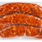 Three raw, seasoned Comeaux’s Alligator Boudin sausage links in a clear plastic package.