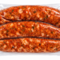 Three raw Comeaux’s Fresh Jalapeno Sausage links in a vacuum-sealed plastic package.