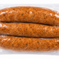 Three raw Comeaux’s Pork Boudin Jalapeno sausages with visible green pepper flecks in a vacuum-sealed package.