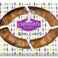 A Cartozzo’s Traditional Cinnamon King Cake in a rectangular purple, green, and gold diamond-patterned box.