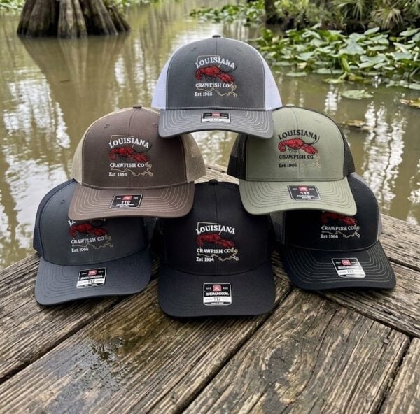 logo trucker A stack of five LA Crawfish Co. leather patch hats resting on a wooden dock over the water.
