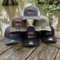 A stack of five LA Crawfish Co. leather patch hats resting on a wooden dock over the water.