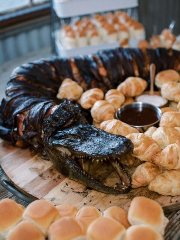 whole gator presentation A whole Louisiana skinned alligator served on a wooden board with small rolls and dipping sauces.