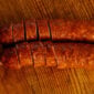 Two sliced links of The Best Stop Smoked Pork Sausage with Garlic on a wooden cutting board.