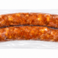 Two vacuum-sealed links of The Best Stop Smoked Pork Sausage with visible Pepper Jack cheese and spices.