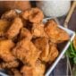 A white bowl of golden-brown 4 lb Alligator Nuggets next to a seasoned lemon half and parsley.