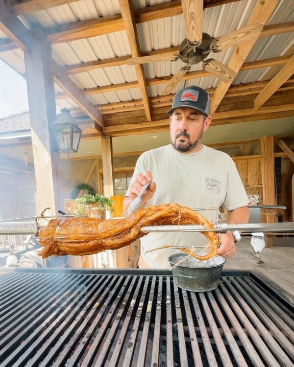 alligator tail on the grill no words A man grills a bone-in whole skinned alligator tail on a rotisserie over a charcoal grill.