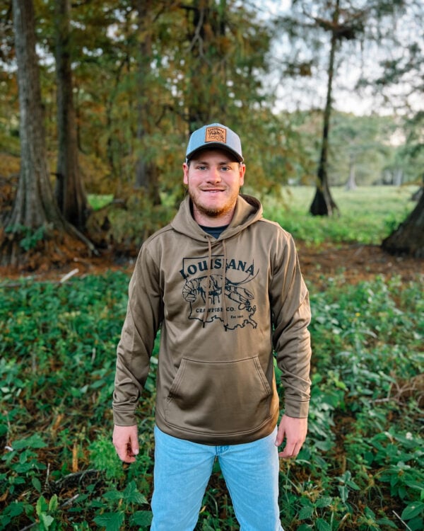 brown hoodie 2 A man outdoors wearing a baseball cap and a light brown LA Crawfish Co. Sport-Tek hoodie with a crawfish graphic.