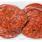 Vacuum-sealed 1 lb package of herb-speckled Bougie Bologna Classic slices, arranged in an overlapping pattern.
