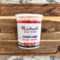 A tub of Rachael’s Sampler frozen seafood gumbo on a wooden cutting board.