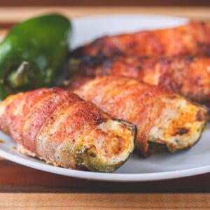 Shrimp and pepper jack stuffed jalapeno poppers, some sliced open, with Cajun meats visible in the background.