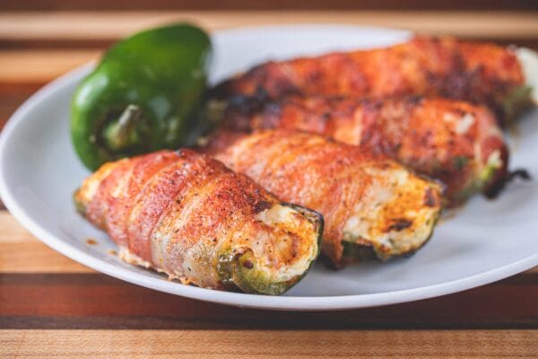 Shrimp and pepper jack stuffed jalapeno poppers, some sliced open, with Cajun meats visible in the background.
