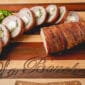 Sliced, bacon-wrapped pork tenderloin stuffed with cream cheese and jalapeño on a board, with extra jalapeño slices nearby.