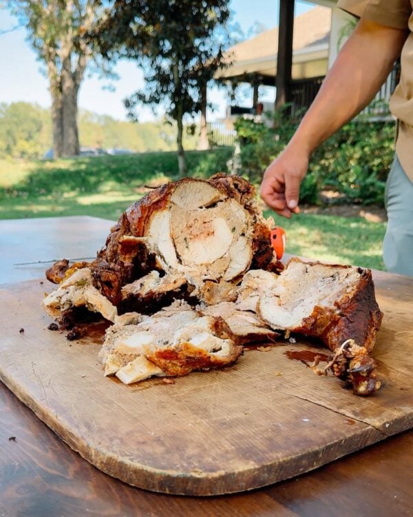15 lb turducken cut A person slices a 15 lb LA Crawfish Co. Turducken on an outdoor wooden cutting board.