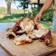 A person slices a 15 lb LA Crawfish Co. Turducken on an outdoor wooden cutting board.