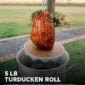 A 5 lb LA Crawfish Co. Turducken Roll in netting hangs from a hook over a large metal pot.