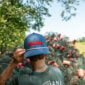 Person from behind wearing a blue LA Crawfish Co. hat, facing a large pile of wire traps.