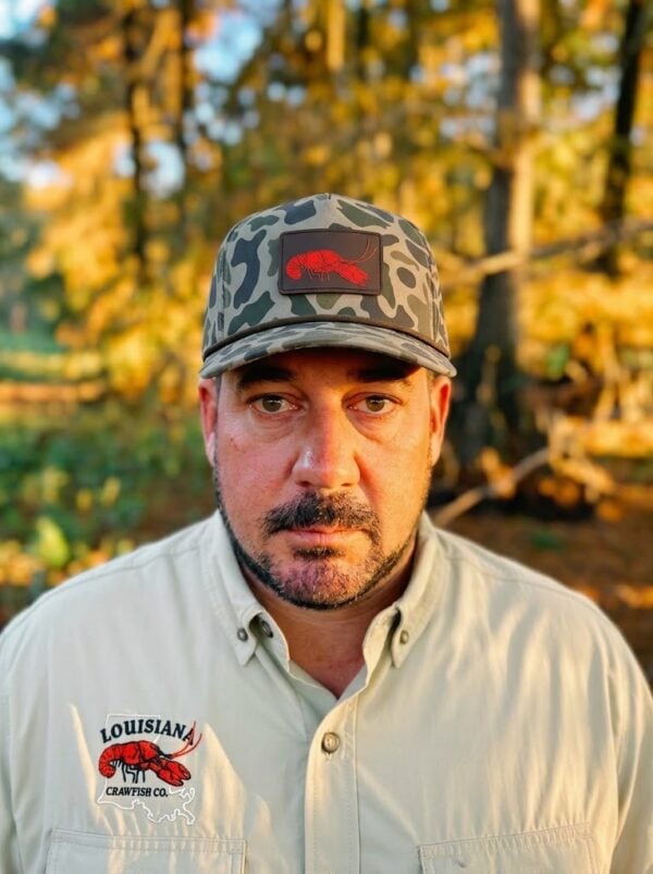 A man wears a matching shirt and an LA Crawfish Co. Coastland PVC patch hat featuring a red crawfish.