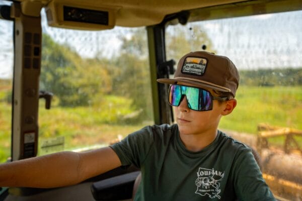 BMO06063Large__25868.1754505773.1280.1280.jpg A young person wearing an LA Crawfish Co. Grandpa Hat dreams of Louisiana crawfish during a sunny green taxi ride.