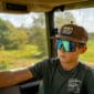 A young person wearing an LA Crawfish Co. Grandpa Hat dreams of Louisiana crawfish during a sunny green taxi ride.