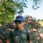 A boy in a crawfish backwards hat stands by fishing nets and buoys, enjoying the sun and thinking of Louisiana seafood.