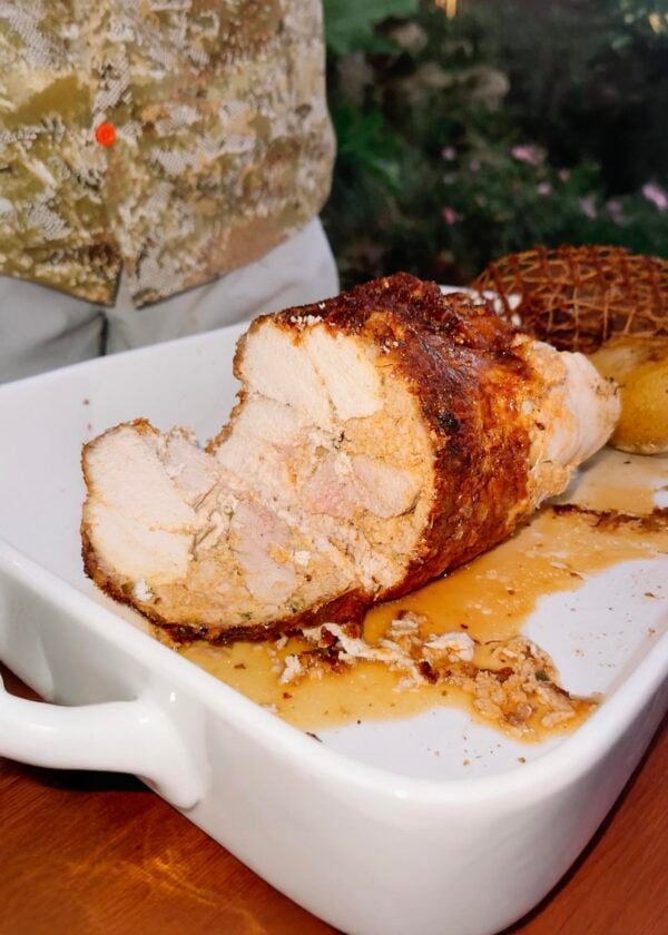 turducken roll cut open A sliced, roasted 5 lb LA Crawfish Co. Turducken Roll with stuffing in a white baking dish.