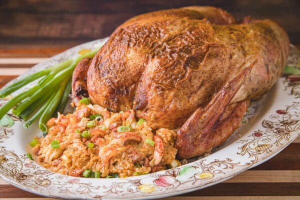 15lb_craw_jamb__62467.1760541128.1280.1280.jpg A 15 lb La Boucherie Turducken sits on a platter with rice stuffing, Cajun meats, and green onions alongside.