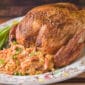 A 15 lb La Boucherie Turducken sits on a platter with rice stuffing, Cajun meats, and green onions alongside.