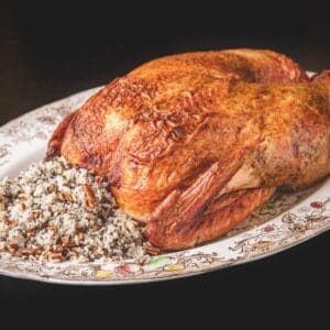 A 15 lb La Boucherie Turducken on a platter, served with wild rice, pecans, and Cajun meats for a Southern feast.