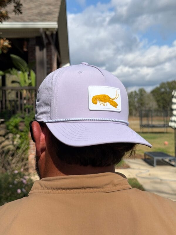 A person wears the Purple and Gold Golf Hat outside, perfect for fans of Louisiana seafood and Cajun cuisine.