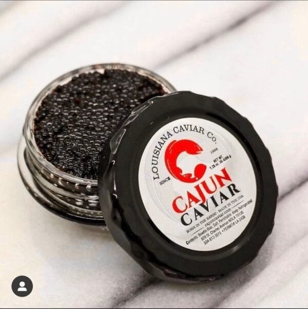 A tin of Cajun Caviar, a Louisiana delicacy, sits open on a white marble surface.