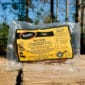 A sealed The Bougie Bundle rests on outdoor wood, ideal for fans of Cajun meats and Louisiana crawfish flavors.