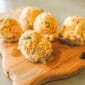 Five scoops of Rachael’s Sampler, speckled with green flecks, sit neatly on a wooden serving board.