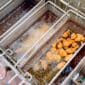 Chicken nuggets frying in hot oil next to classic Louisiana seafood, with some pieces golden brown and others still cooking.